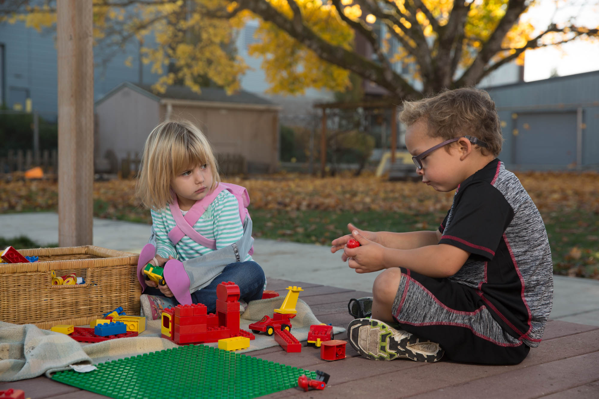two kids playing with legos outside